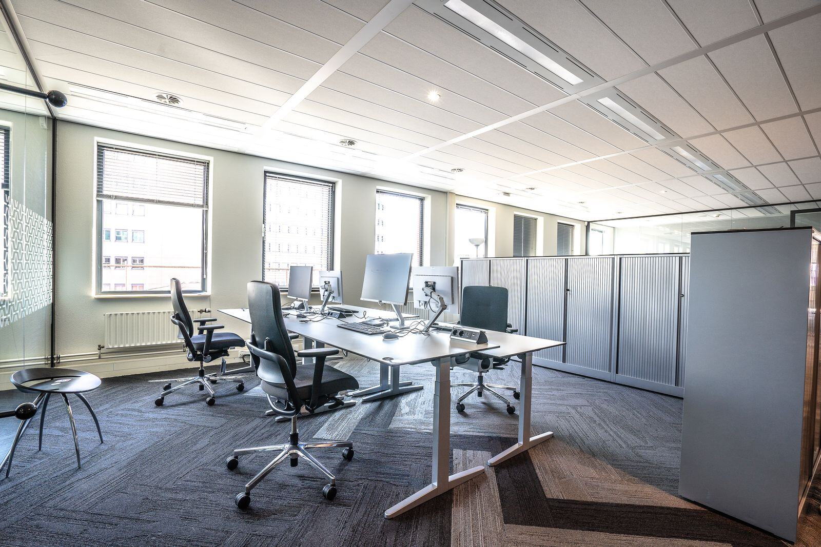 Plateau de bureaux avec postes de travail et fauteuils ergonomiques face aux baies vitrées