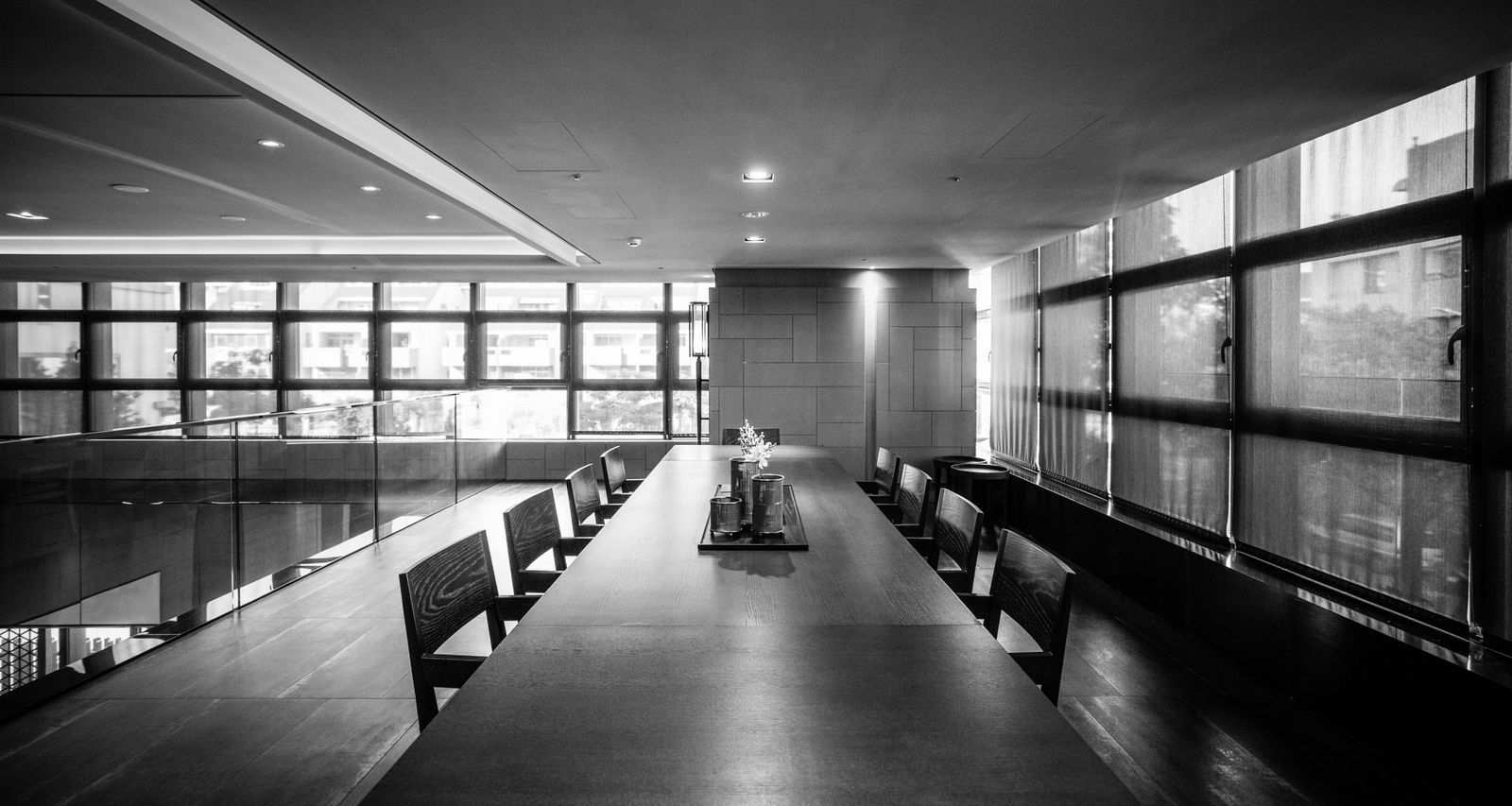 Longue table de réunion sombre et fauteuils noirs dans une salle vitrée, aménagement tertiaire